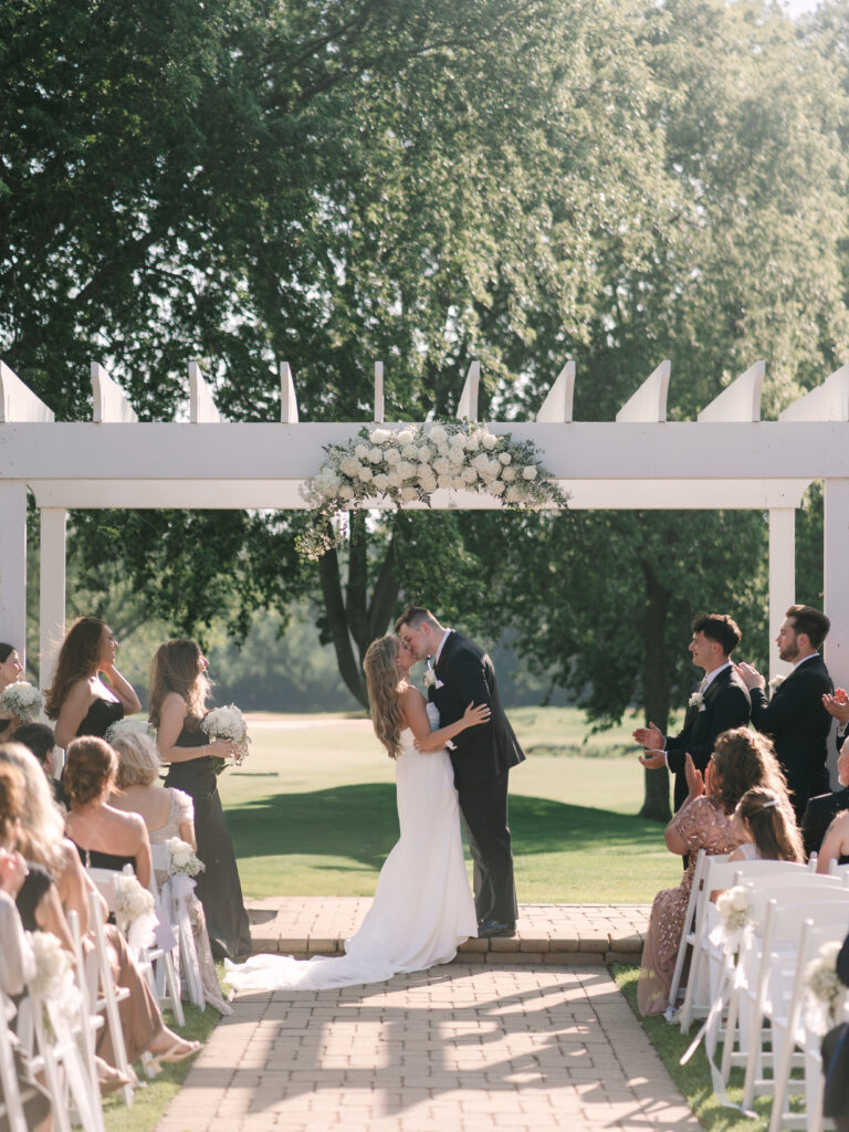Bride and groom kiss down the aisle after ceremony at Arrowhead Golf Club wedding, joyful celebration in Naperville.