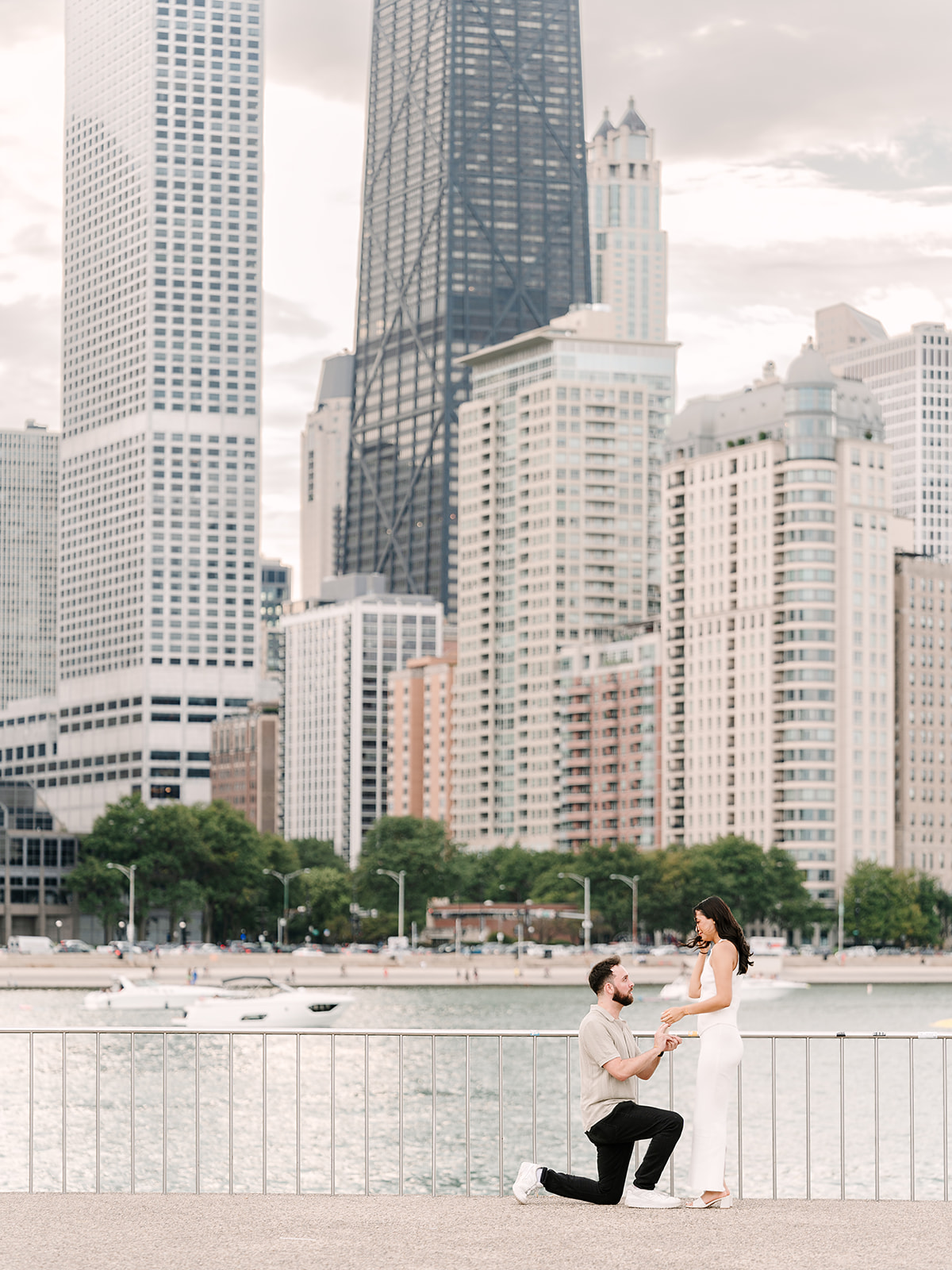 Man down on one knee proposing at Milton Lee Olive Park with the Chicago skyline behind them